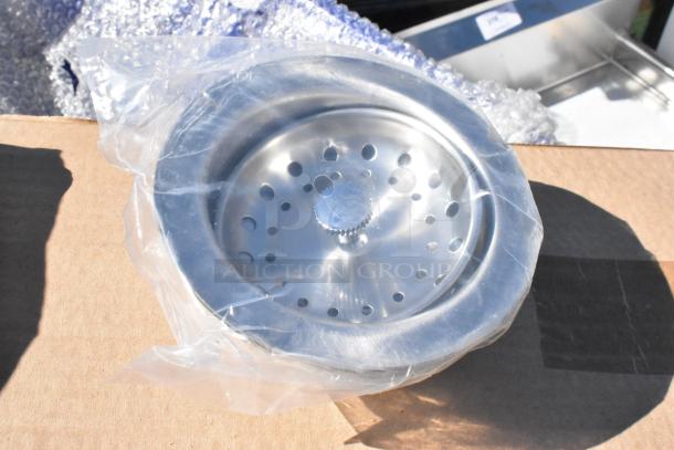 Alt text: Stainless steel sink strainer, new, in packaging. Part of a scratch and dent stainless steel single bay sink, no legs.