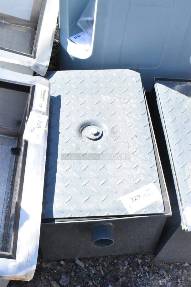 Brand new scratch and dent metal commercial grease trap with diamond plate lid, showing visible markings and pipe outlet.