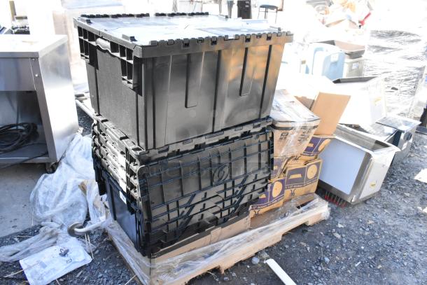 Stack of black bins on a pallet with various packed items, including boxes labeled for round amber plate covers. Items appear brand new.