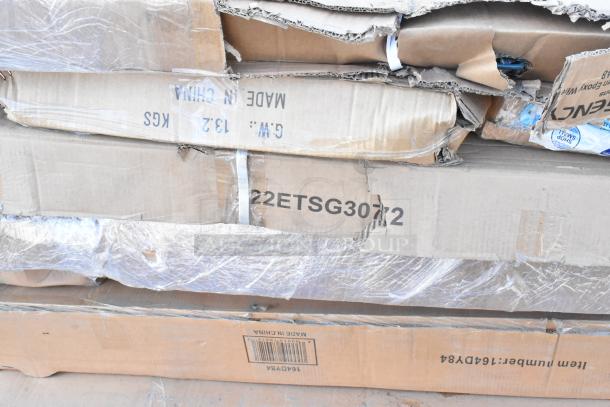 Stack of cardboard boxes labeled with item codes, partially opened, showing scratch and dent packaging.