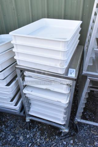 Metal pan transport rack with commercial casters, featuring stacked white poly dough bins, in good condition.