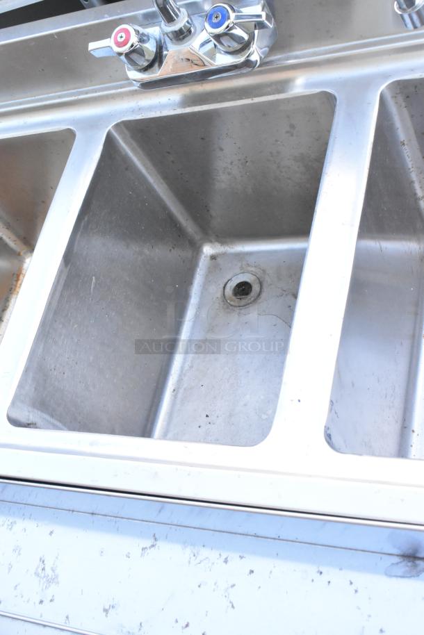 Stainless steel 3-bay back bar sink with dual side drain board, double speedwell, faucet, and handles. Slight wear visible.