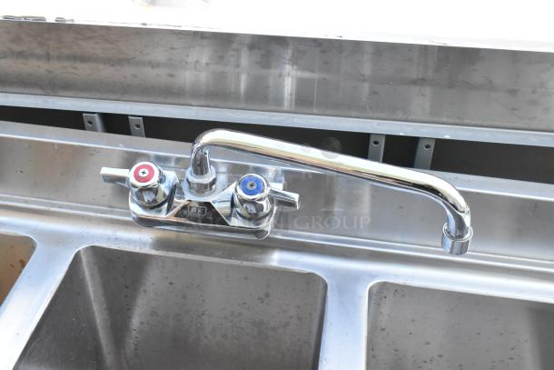 Stainless steel 3 bay back bar sink with dual side drain boards, double speedwell, and faucet with hot/cold handles.