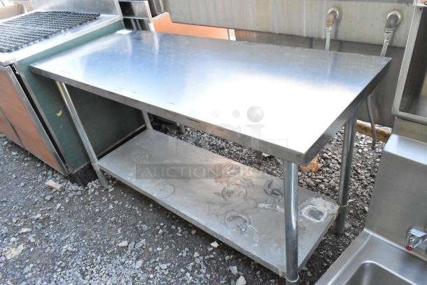 Stainless steel table with metal under shelf, showing wear on the lower surface. Ideal for industrial or kitchen use.