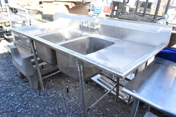 Stainless steel 2-bay sink with dual drain boards, faucet, and handles in good condition, ideal for commercial use.