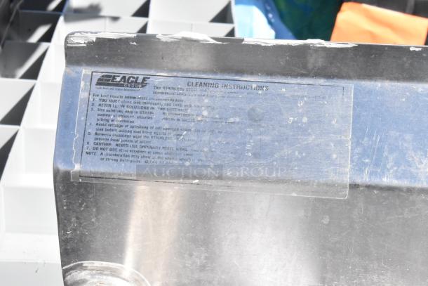 Stainless steel 2-bay sink with dual drain boards, faucet, and handles. Features Eagle Group cleaning instructions. Marked and worn.