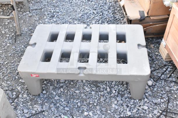 Two gray Metro poly dunnage racks on gravel, sturdy design, slight wear, featuring a Metro logo.