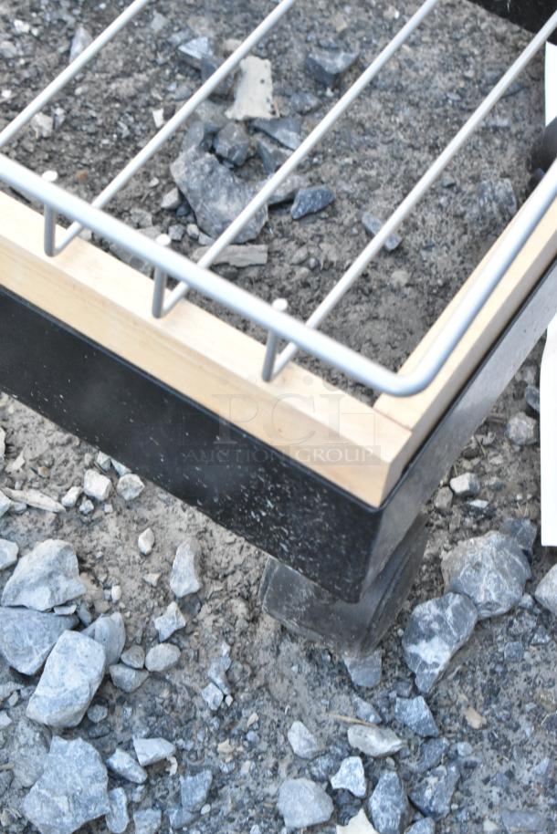 Sturdy metal display rack on casters. Features a wooden frame and wire grid. Moderate wear, suitable for retail use.
