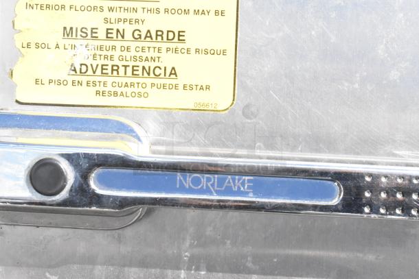 Norlake Walk In Cooler detail with brand marking, warning label about slippery floor, silver finish.