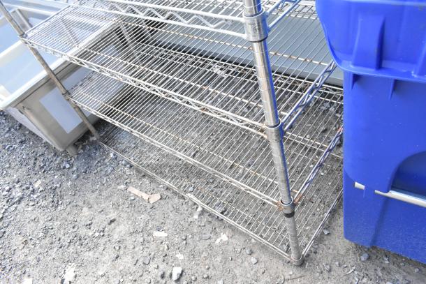 Chrome finish 5-tier wire shelving unit, used condition, visible on gravel. Buyer must dismantle and consider freight charges.