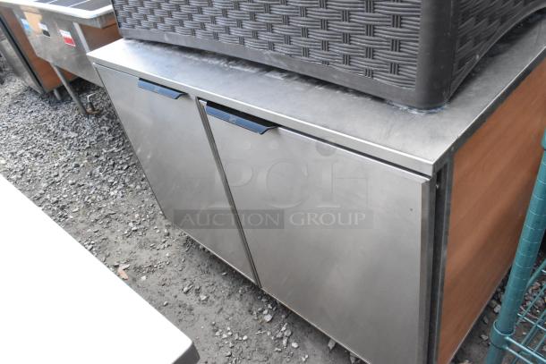 Duke stainless steel commercial 2-door work top counter, featuring durable construction. Slight wear visible on surface. Ideal for kitchens.