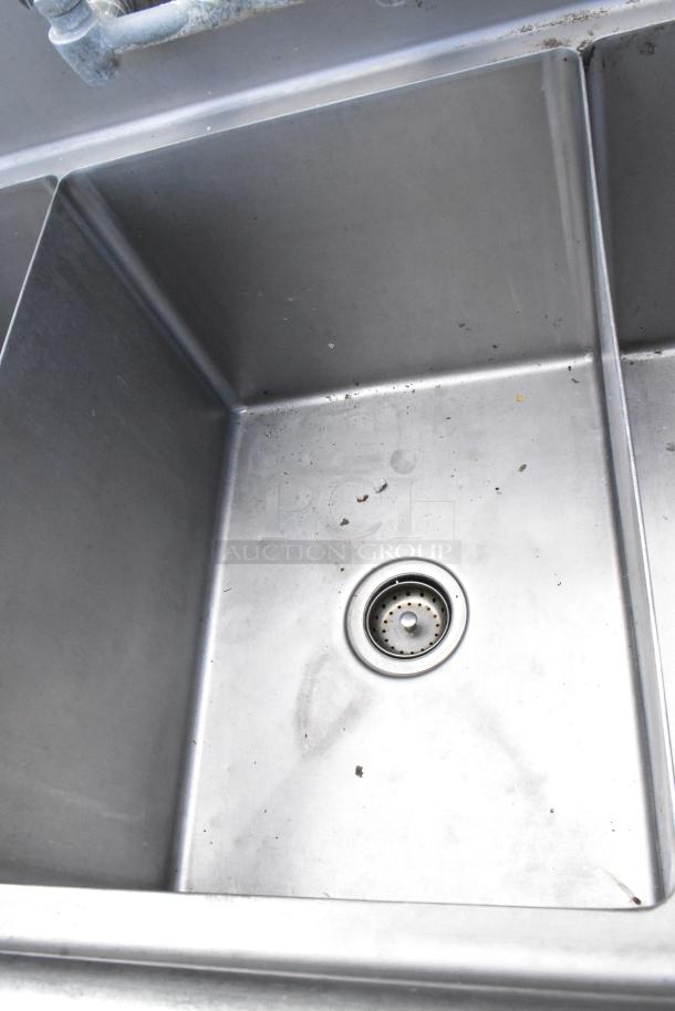 Stainless steel commercial 3 bay sink with dual drain boards, lightly used, durable construction, visible dirt in corners.