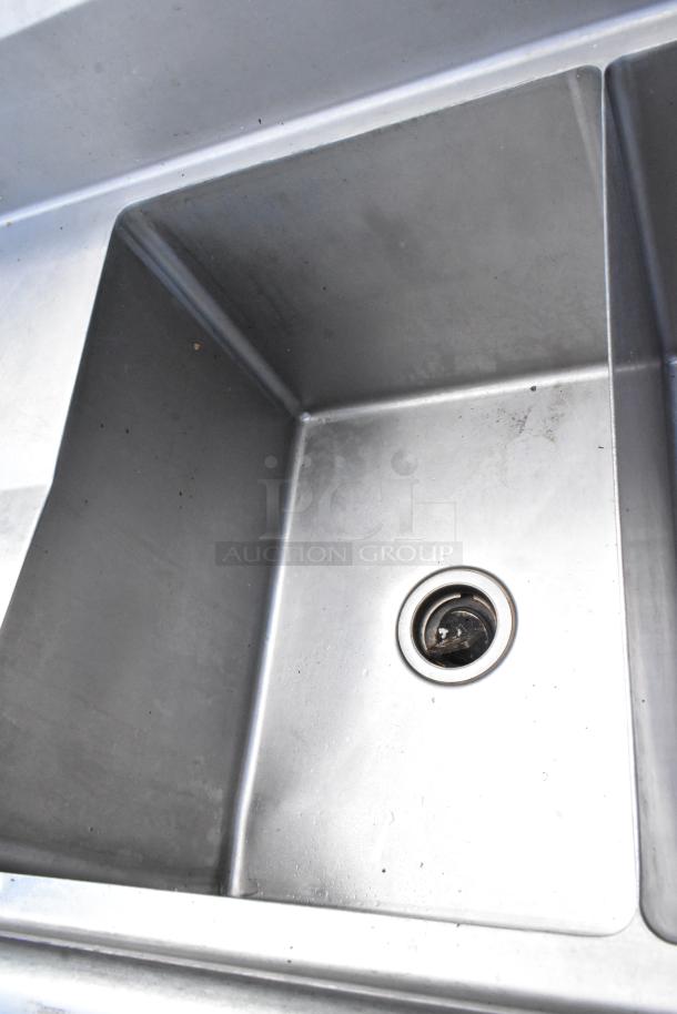Stainless steel commercial 3 bay sink with dual drain boards, featuring clean surfaces and visible drainage details.