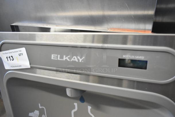Brand new Elkay water fountain with bottle filler, scratch and dent condition. Visible label: "BOTTLES SAVED." Auction tag: 113.