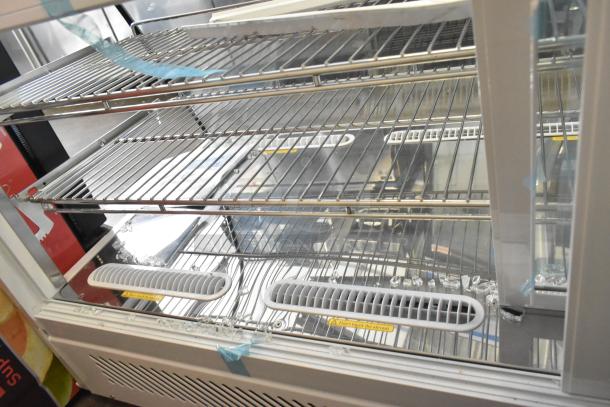 Brand new Avantco metal countertop display case merchandiser, missing side panels, visible vents, and glass shards at the base.
