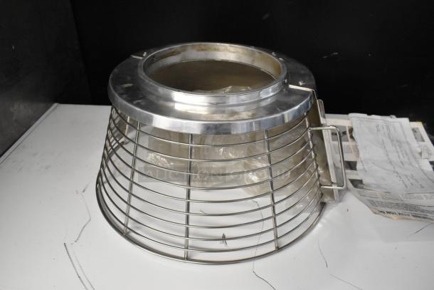 Stainless steel metal bowl guard for mixer, featuring a sturdy wire design and handle, showing slight wear.