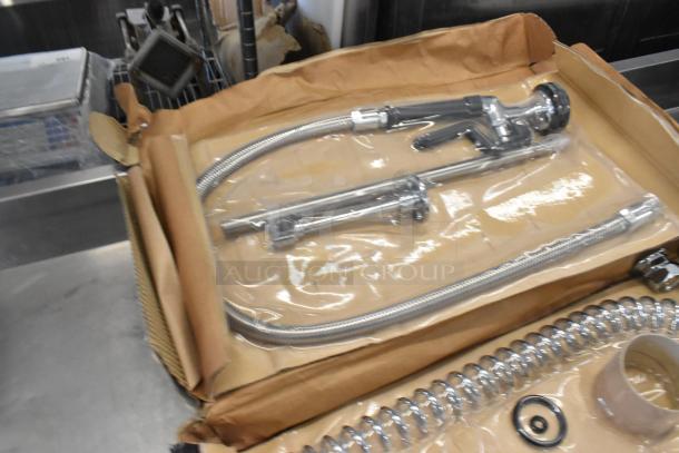 Brand new Regency 600PRD4X pre-rinse faucet in packaging, chrome finish, 1.15 GPM, deck-mounted, slight scratches noted.