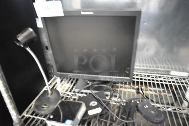 Lenovo computer monitor on metal rack, showing front view, with cables and accessories.