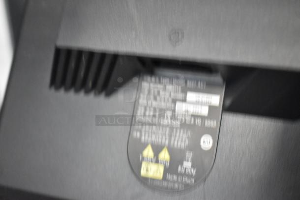 Blurry close-up of a computer monitor's label showing some text and symbols, indicating model and specifications.