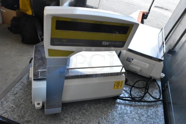 Easy Weigh LS-100 metal countertop scale, 240V, 1 phase. Features digital display, sturdy design. Model details on front panel.