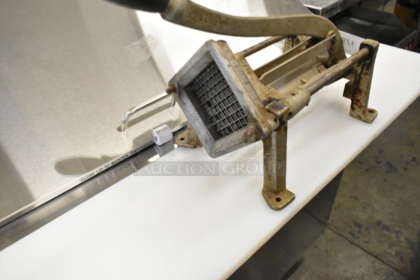 Metal countertop French fry cutter with rust on frame, grid blade, and sturdy base, suitable for commercial kitchen use.