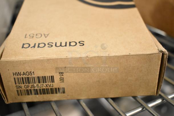 Cardboard box labeled "samsara" with barcodes and serial numbers on a metal shelf.