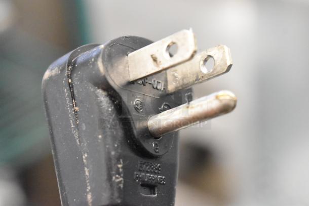 Close-up of a three-prong electrical plug, possibly for a Frigidaire appliance; details imprinted on plug body.