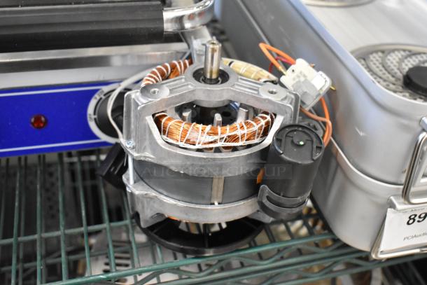 Electric motor with visible copper wiring and metal casing, in good condition, mounted on a metal shelf.