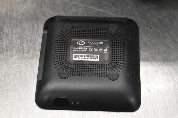 Cloudcover G9CX device labeled with model and certifications, featuring a unique MAC address, set on a textured surface.