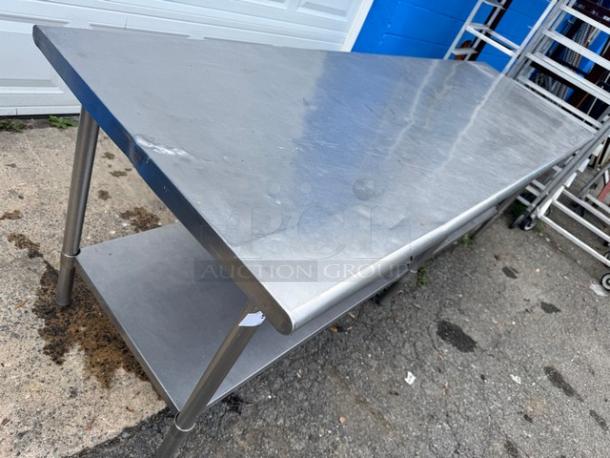 8ft stainless steel work table with undershelf, minor surface wear, sturdy build, ideal for kitchen or industrial use.
