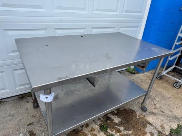 60" stainless steel work table with undershelf, featuring caster wheels for mobility. Slight surface wear visible.