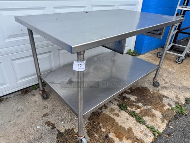 60" stainless steel work table with undershelf, on wheels, in used condition, tag labeled "10" attached.