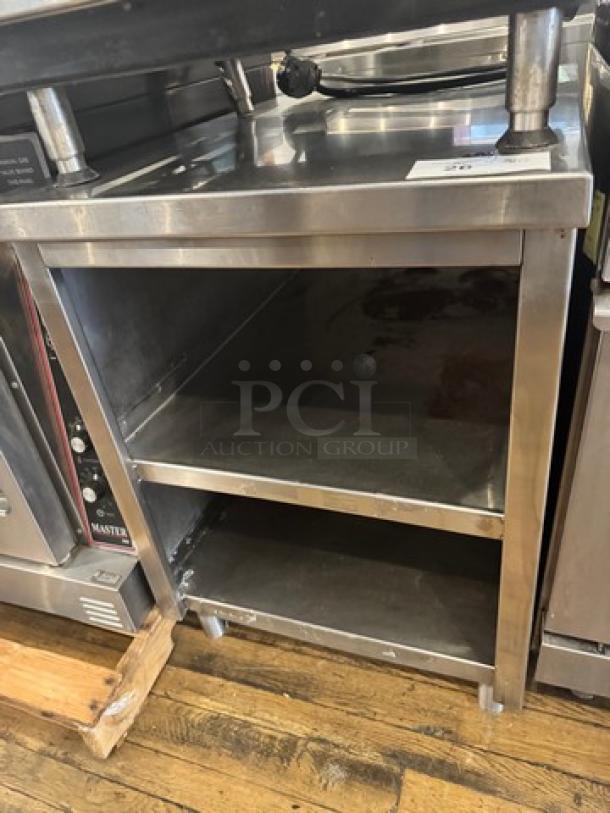 Stainless steel stand with two shelves, sturdy construction, used condition, suitable for kitchen storage or industrial use.