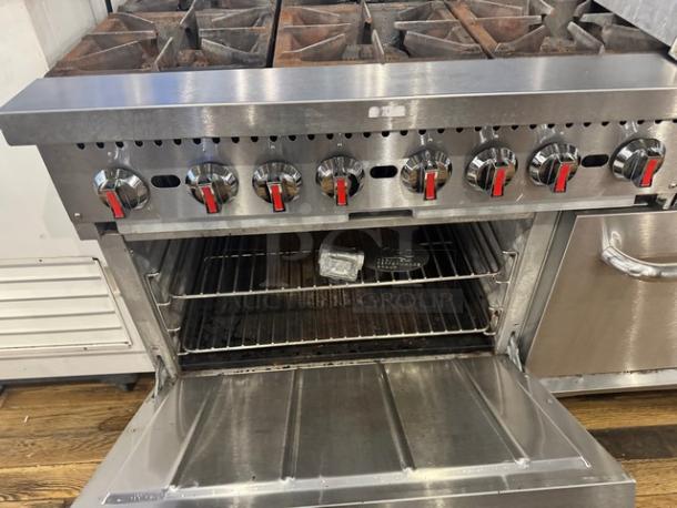 CPG natural gas stove with 6 burners, 24" griddle, and stainless steel finish on legs. Open oven showing racks inside.