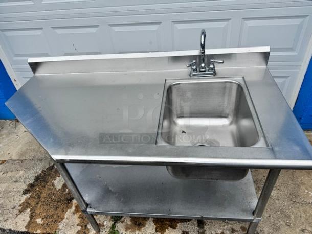Stainless steel 60" sink with table, featuring a broken faucet. Includes backsplash and lower shelf, in used condition.