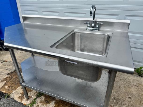 Stainless steel 60" sink with table; features a broken faucet, single basin, undershelf, and backsplash, in used condition.