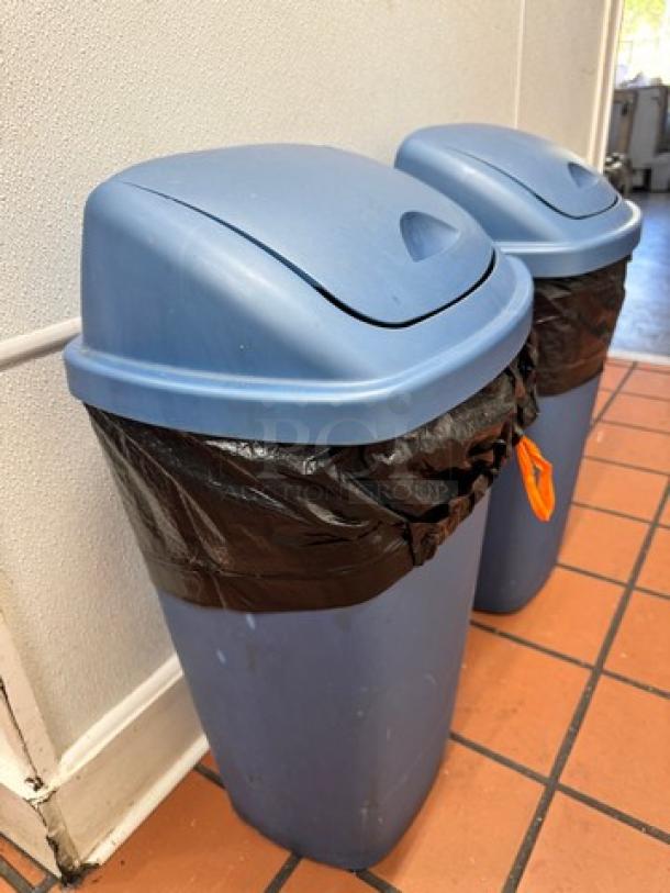 Two blue swing top waste cans with black liners, labeled "BIDX2," on tiled floor; good condition.
