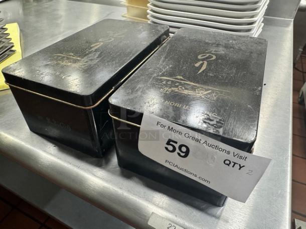 Lot of 2 black aluminum storage boxes with decorative gold design and text. Slightly worn. Auction tag: 59, qty 2.