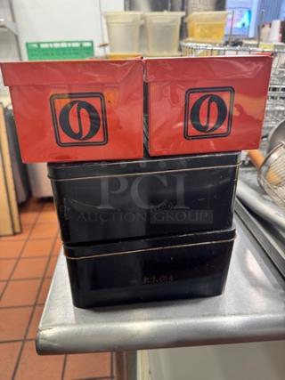 Lot of 4 aluminum storage boxes, 2 red with logos, 2 black, used condition. Stackable design for efficient storage.