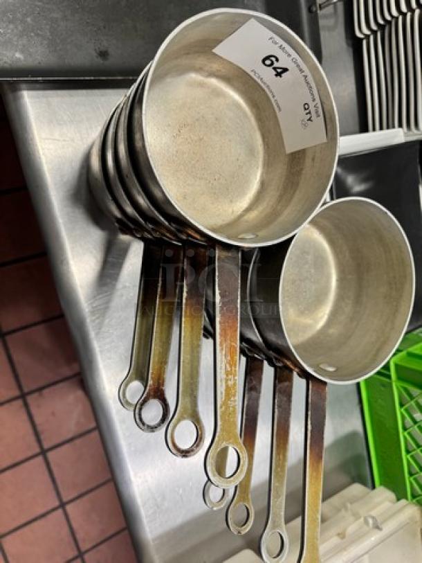 Six stackable 6" saucepans with long handles, showing moderate wear. Label indicates lot number 64, quantity 8.