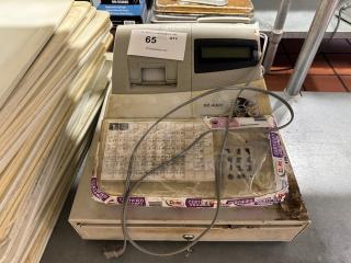 Cash register, model XE-A302, worn condition, features label for auction lot 65, with visible cables and certified service stickers.
