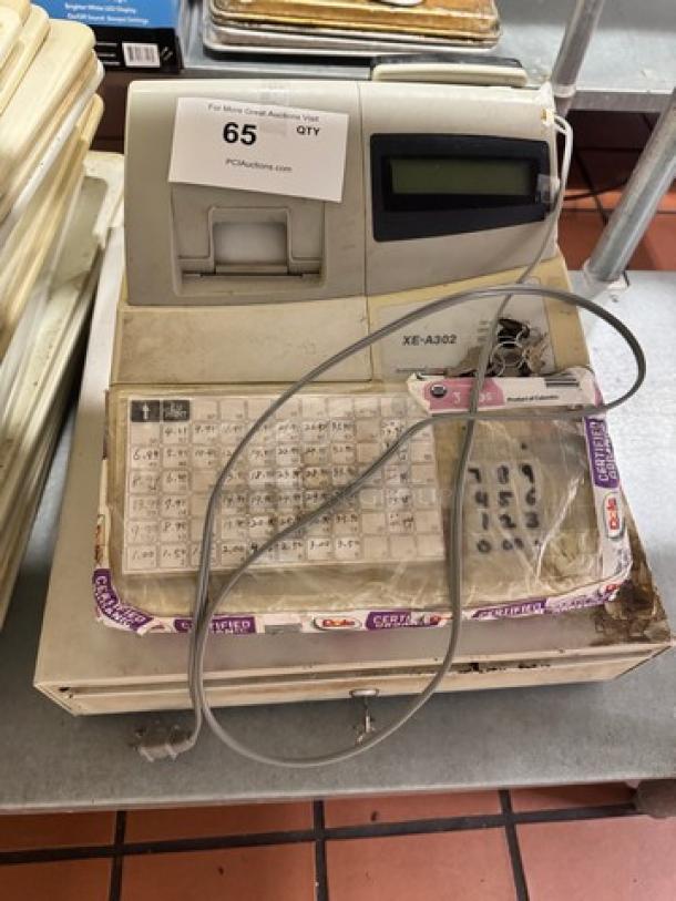 Alt text: Sharp XE-A302 cash register with visible wear, numeric keypad, display screen, power cord, and lot tag.