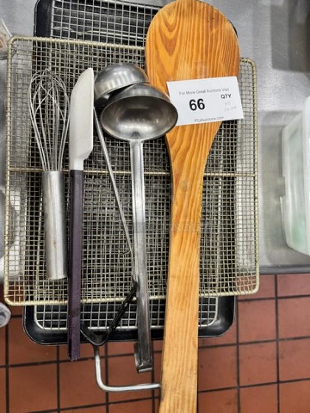 Miscellaneous kitchenware including a whisk, knives, ladles, and a large wooden spoon displayed on a wire rack. Auction tag 66 visible.