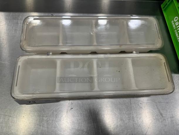 Lot of 2 plastic condiment holders with clear lids, featuring four compartments each. Used condition with minor wear.