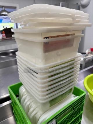 Stack of plastic food pans with lids, used condition, neatly organized in a green crate.