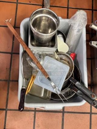 Assorted kitchenware in a bin, including stainless steel pots, pans, utensils, and plastic containers. Used condition.