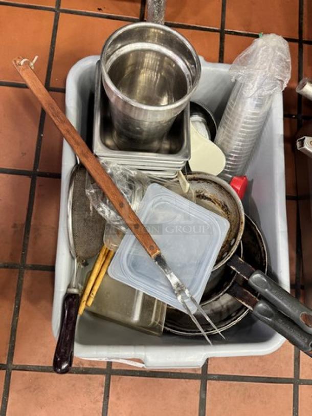 Assorted kitchenware including pots, pans, cutlery, and storage containers in a bin; mixed condition.
