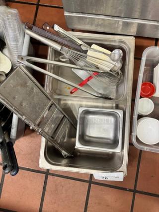 Assorted kitchenware including whisk, spatula, tongs, ladle, and slicer in various metal pans, condition used.
