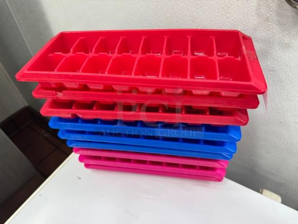 Lot of 9 colorful ice cube trays in red, blue, and pink. All in good condition, stacked neatly.