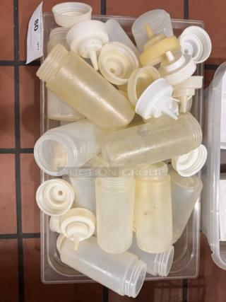 Tray of assorted squeeze bottles with white caps, used condition. Ideal for bulk purchase, exact quantity unspecified.